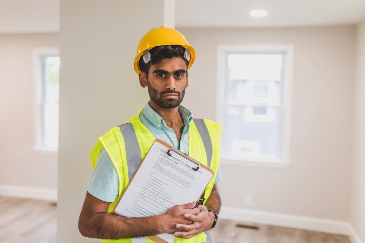 Engineer in hard hat reviewing specifications on a clipboard